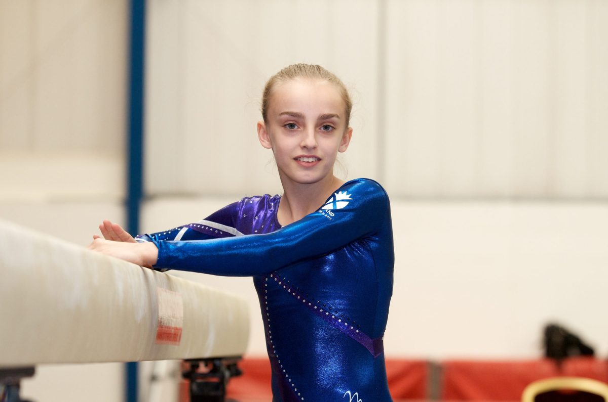 Gymnast Shannon Archer standing beside the beam in Team Scotland leotard