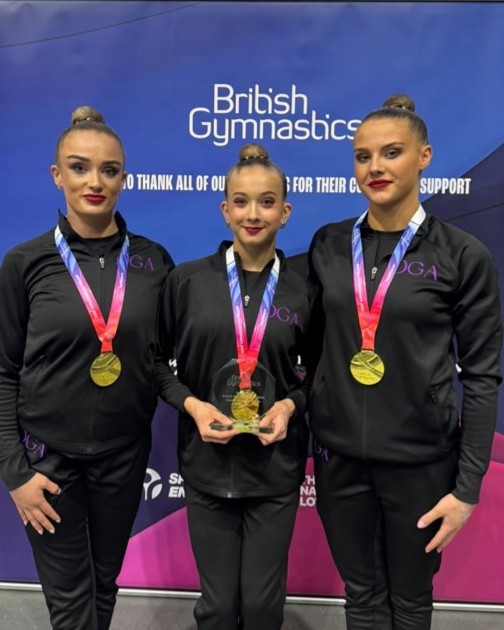 Karla, Gemma and Emma stand side by side with their senior women's gold medals and 2025 British Acrobatics Championships glass trophy.