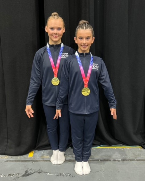 Millie and Georgia from East Kilbride standing with the gold 2025 British Acrobatic Championships medals