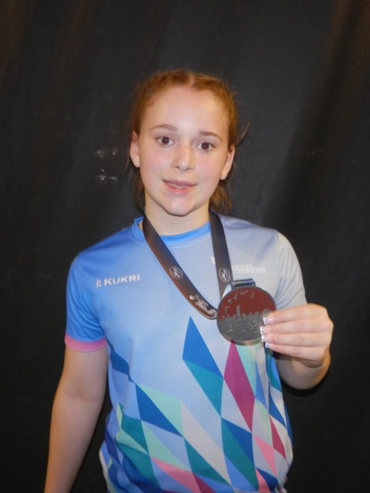 Millie Flynn holds up her 13-14 years womens bronze medal for DMT at the 2025 Loule Cup
