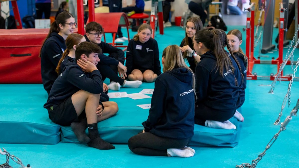 Young male and female members of the Scottish Gymnastics youth forum chatting in a gym